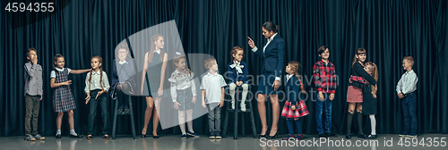 Image of Cute stylish children on dark studio background. The beautiful teen girls and boy standing together