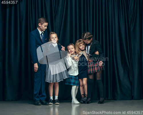 Image of Cute stylish children on dark studio background. The beautiful teen girls and boy standing together