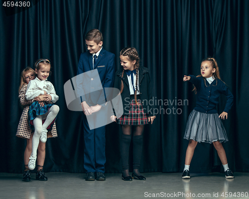 Image of Cute stylish children on dark studio background. The beautiful teen girls and boy standing together