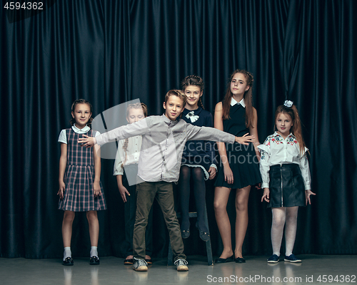 Image of Cute stylish children on dark studio background. The beautiful teen girls and boy standing together