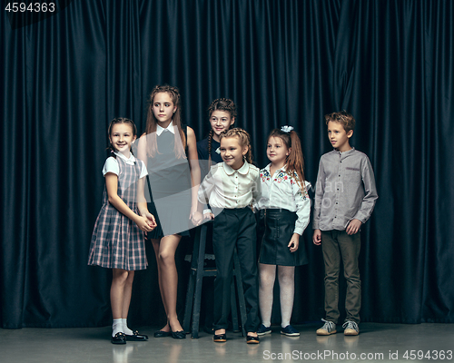 Image of Cute stylish children on dark studio background. The beautiful teen girls and boy standing together
