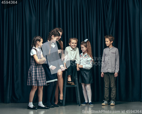 Image of Cute stylish children on dark studio background. The beautiful teen girls and boy standing together