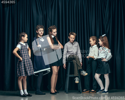 Image of Cute stylish children on dark studio background. The beautiful teen girls and boy standing together