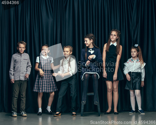 Image of Cute stylish children on dark studio background. The beautiful teen girls and boy standing together