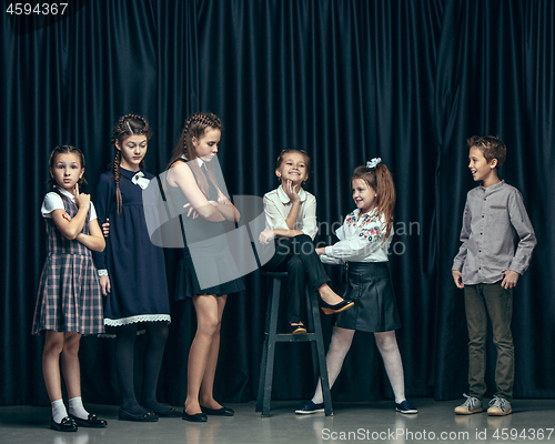 Image of Cute stylish children on dark studio background. The beautiful teen girls and boy standing together