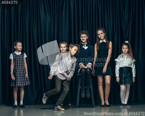 Image of Cute stylish children on dark studio background. The beautiful teen girls and boy standing together