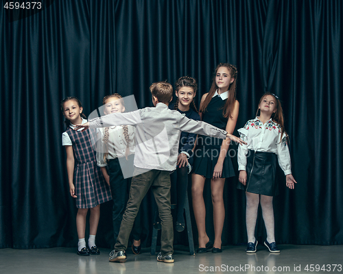 Image of Cute stylish children on dark studio background. The beautiful teen girls and boy standing together