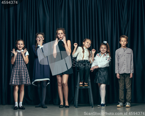 Image of Cute stylish children on dark studio background. The beautiful teen girls and boy standing together