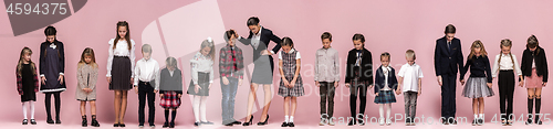 Image of Cute stylish children on pink studio background. The beautiful teen girls and boy standing together