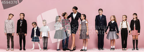 Image of Cute stylish children on pink studio background. The beautiful teen girls and boy standing together