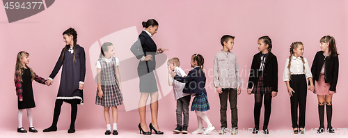 Image of Cute stylish children on pink studio background. The beautiful teen girls and boy standing together