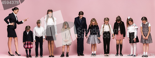 Image of Cute stylish children on pink studio background. The beautiful teen girls and boy standing together