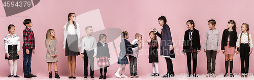 Image of Cute stylish children on pink studio background. The beautiful teen girls and boy standing together