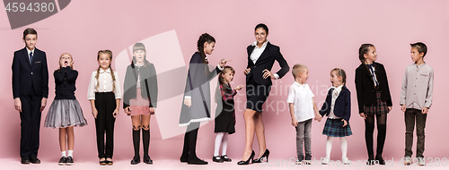 Image of Cute stylish children on pink studio background. The beautiful teen girls and boy standing together