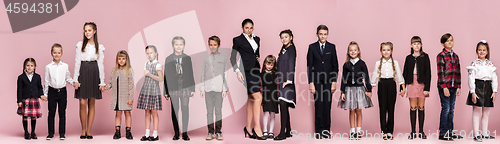 Image of Cute stylish children on pink studio background. The beautiful teen girls and boy standing together