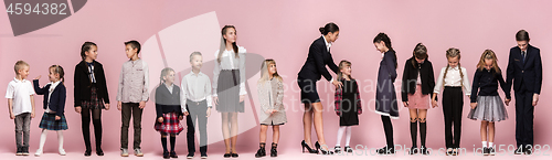 Image of Cute stylish children on pink studio background. The beautiful teen girls and boy standing together