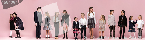 Image of Cute stylish children on pink studio background. The beautiful teen girls and boy standing together