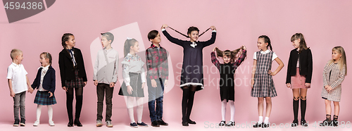 Image of Cute stylish children on pink studio background. The beautiful teen girls and boy standing together