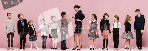 Image of Cute stylish children on pink studio background. The beautiful teen girls and boy standing together