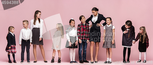 Image of Cute stylish children on pink studio background. The beautiful teen girls and boy standing together