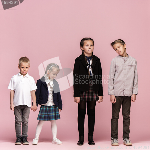 Image of Cute stylish children on pink studio background. The beautiful teen girls and boy standing together