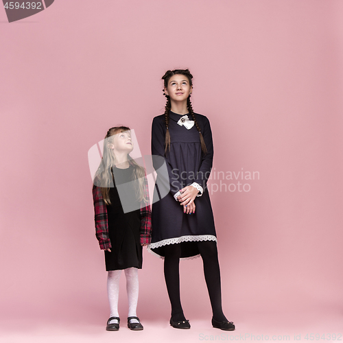 Image of Cute stylish children on pink studio background. The beautiful teen girls standing together