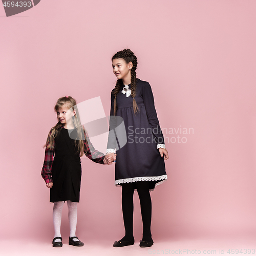 Image of Cute stylish children on pink studio background. The beautiful teen girls standing together