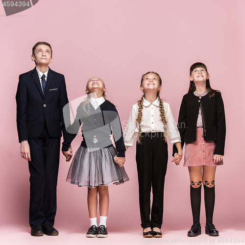 Image of Cute stylish children on pink studio background. The beautiful teen girls and boy standing together