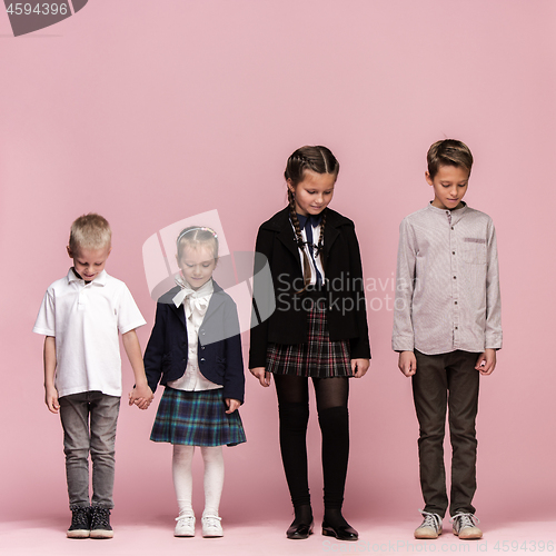 Image of Cute stylish children on pink studio background. The beautiful teen girls and boy standing together
