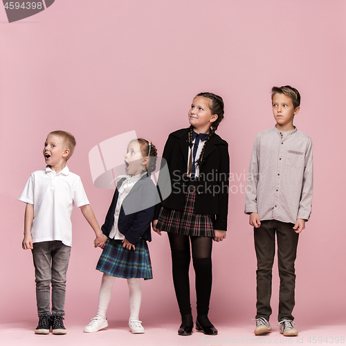 Image of Cute stylish children on pink studio background. The beautiful teen girls and boy standing together
