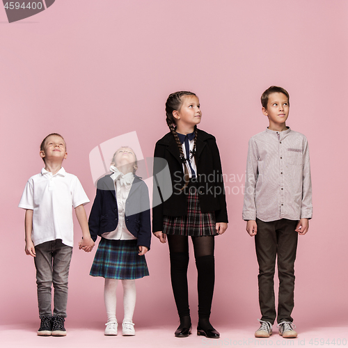 Image of Cute stylish children on pink studio background. The beautiful teen girls and boy standing together