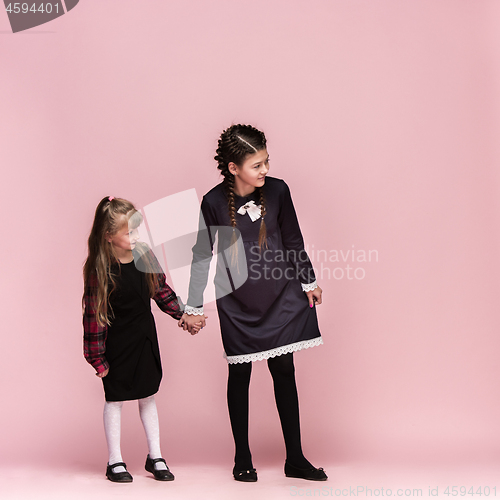 Image of Cute stylish children on pink studio background. The beautiful teen girls standing together