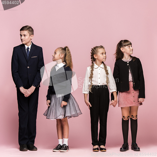 Image of Cute stylish children on pink studio background. The beautiful teen girls and boy standing together