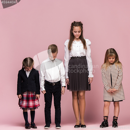 Image of Cute stylish children on pink studio background. The beautiful teen girls and boy standing together