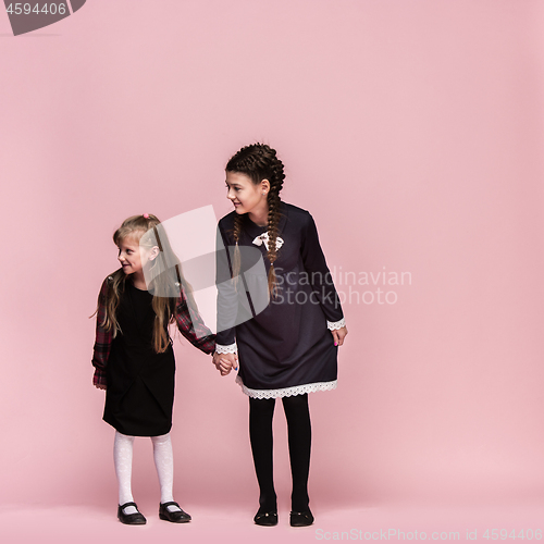 Image of Cute stylish children on pink studio background. The beautiful teen girls standing together