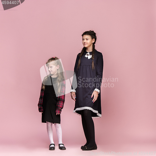 Image of Cute stylish children on pink studio background. The beautiful teen girls standing together