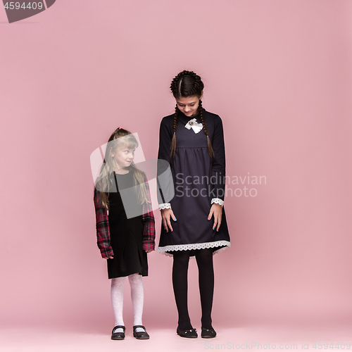 Image of Cute stylish children on pink studio background. The beautiful teen girls standing together