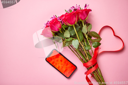 Image of Pink roses bouquet with hart shaped bow and mobile phone with copy space screen