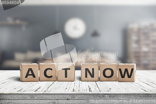 Image of Act now message sign on a wooden desk