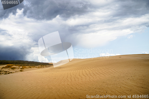 Image of Sand dune in a desert with dark clouds