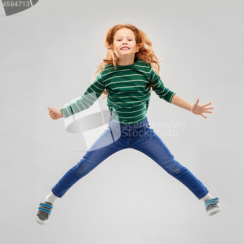 Image of smiling red haired girl in striped shirt jumping