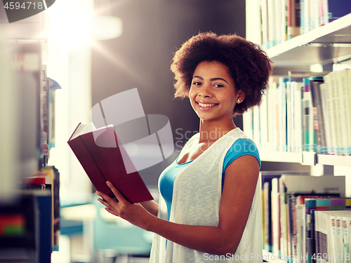 Image of happy african student girl reading book at library