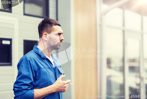 Image of auto mechanic smoking cigarette at car workshop