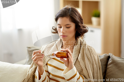 Image of sick woman with antipyretic or cough syrup at home