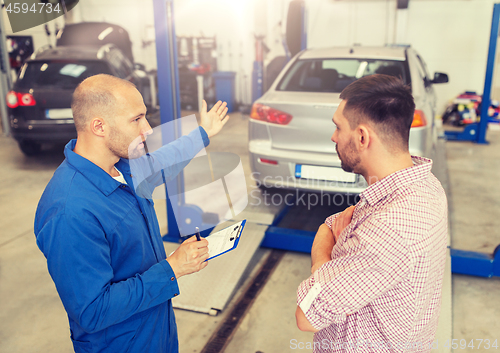 Image of auto mechanic with clipboard and man at car shop