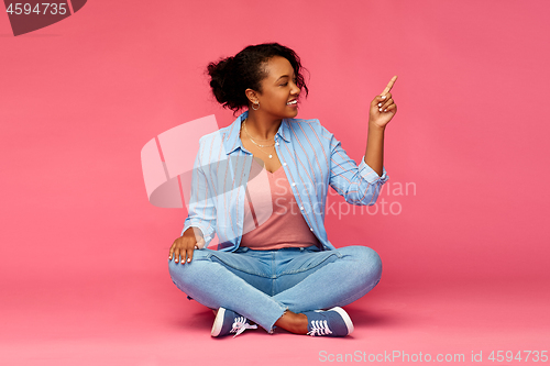 Image of happy african american woman pointing finger up