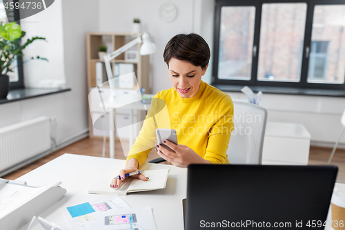 Image of smiling ui designer using smartphone at office