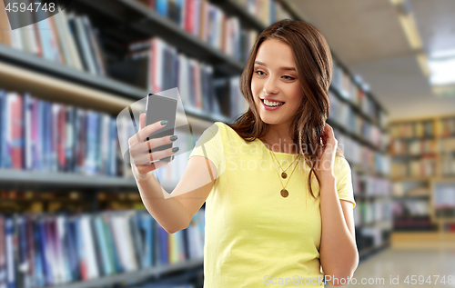 Image of smiling teenage girl taking selfie by smartphone