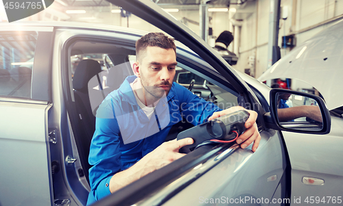 Image of mechanic man with diagnostic scanner at car shop