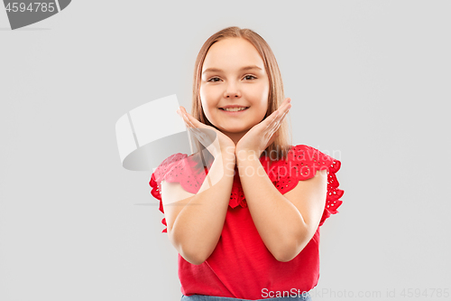 Image of smiling girl in red shirt posing over grey